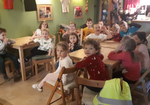 na zdjęciu dzieci z gr ,,Misie” siedzące przy stolikach i oczekujące na przedstawienie w ,,Baśniowej Kawiarence”.